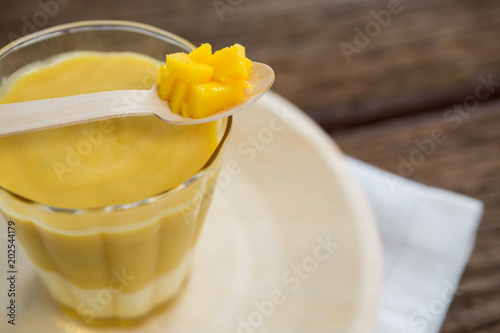 Fresh glass of smoothie kept on plate with pineapple in spoon
