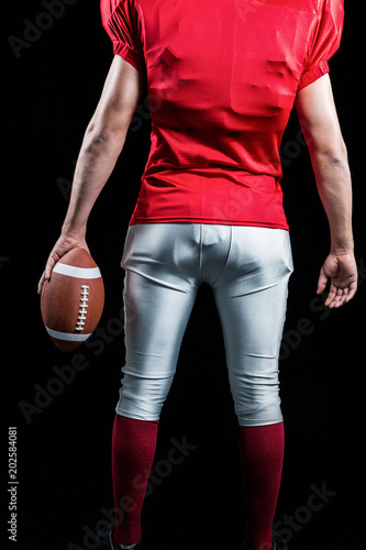 Mid section of American football player with ball
