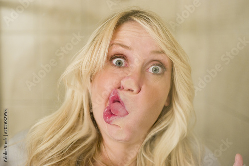 Blonde woman smashing face against window silly look