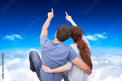 Couple sitting on floor together against bright blue sky over clouds