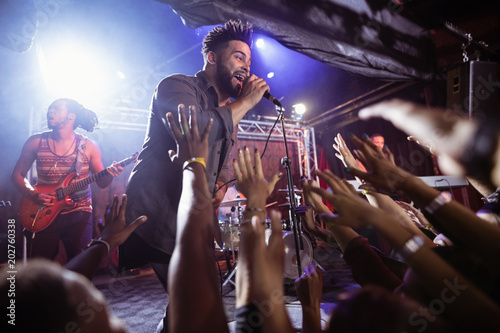 Male singer performing on stage by crowd at nightclub