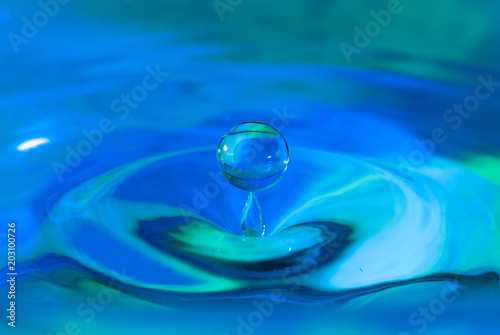 pure water droplet splashing on water surface forming beautiful shapes abstract concept blue hue photo