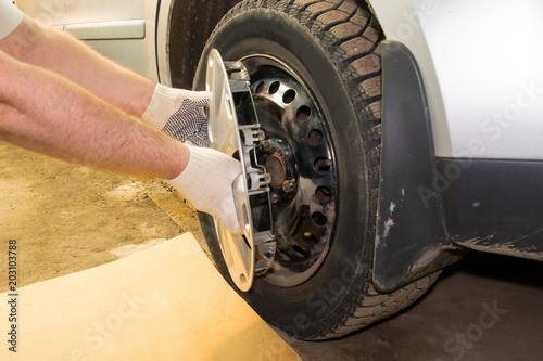 A mechanic removing the hubcap from a car wheel. Tire fitting.