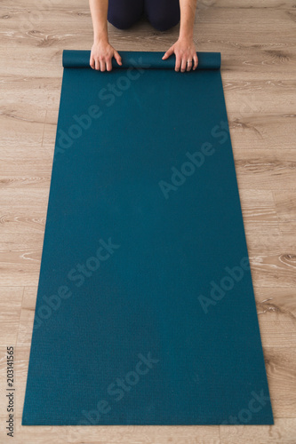 Woman laying out yoga mat in a studio