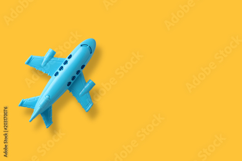 blue plastic toy plane on yellow background with space 