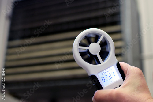 Hand-held anemometer measuring air flowing of ventilation louvres of the industrial ventilation unit.