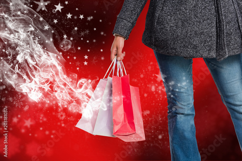 Smiling woman holding shopping bag against blurred snowflake design