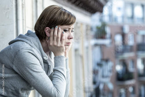 young attractive unhappy depressed lonely woman looking sad on the balcony at home