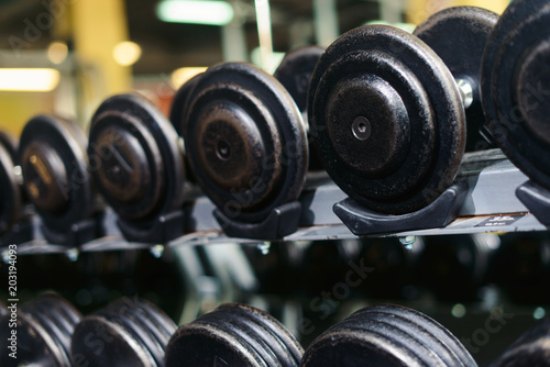Rows of dumbbells in the gym with hign contrast and monochrome color tone with bright sunlight. Sport and health bodybuilding concept