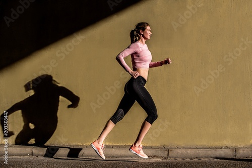Young fit blonde woman running in the street