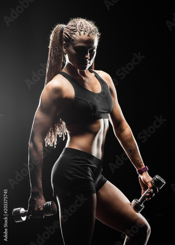 Sports girl with dumbbells on a black background