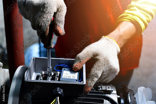 Electricians working on industrial panels, installing and assembling new wires.