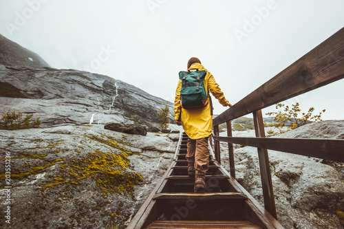 Tourist woman with backpack climbing up stairs in rocky mountains Traveling alone adventure Lifestyle active vacations in Norway