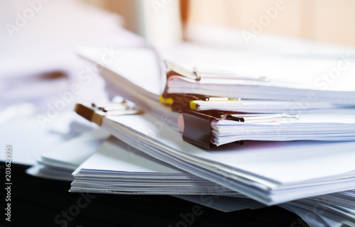 Stack of papers documents in archives files with clip papers on table at offices, Busy offices and Pile of data unfinished folders on office desk indoor near window, Business concept.