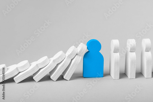 Concept of domino effect in business. The fall of the crumbling business is saved by special employee leader. The line of dominoes from the white figures of the man is falling, one blue man stops fall