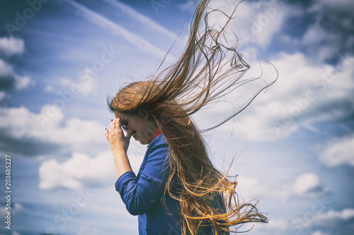 Wind in the hair, beautiful woman in dramatic sky
