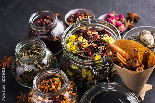 A set of various herbal and fruit teas in glass jars on a dark background. Medicinal herbs. A natural, eco product.