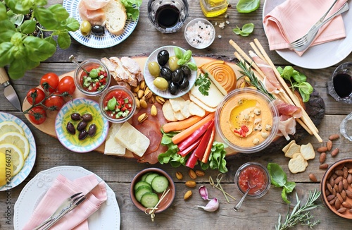 Mediterranean appetizers table concept. Diner table with tapas selection: cured meat and salami, gazpacho soup, jamon, olives, cheese, hummus and vegetables. Overhead view.