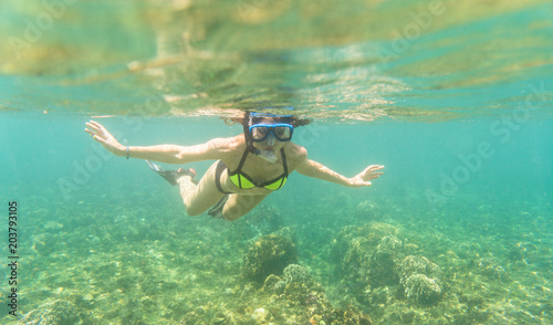 Woman snorkelling over floor of tropical sea in her summer vacation