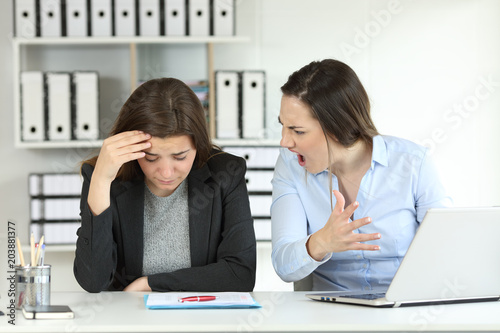 Boss scolding a sad employee at office