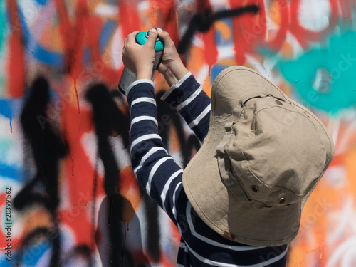Young artist painting graffiti wall bright colours background
