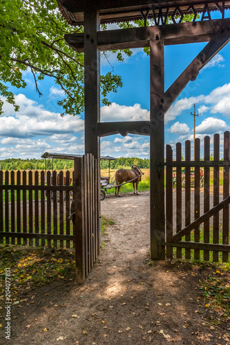 brama wejściowa do Parku Narodowego w Białowieży. W tle widać konia z wozem