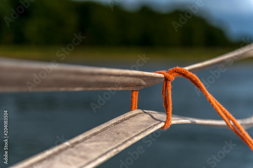 cienki pomarańczowy sznurek zawiązany na pasach (krawat)