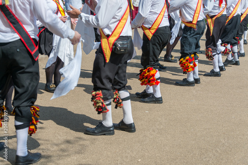 diagonal line of traditional english morris dancers wearing plus fours bells and sashes