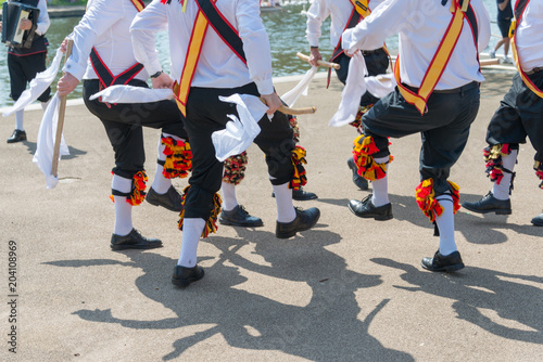 Morris Men wearing bells and white shirts and stockings dance on May Day Bank Holiday with sticks and handkerchiefs