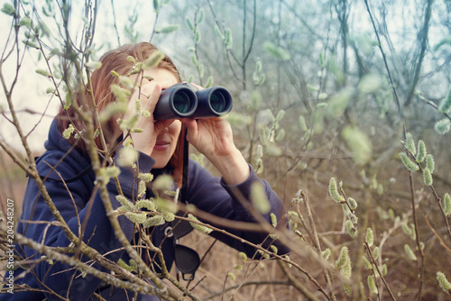 Girl with the binoculars against the background of the nature. Observation of birds. Birdwatching