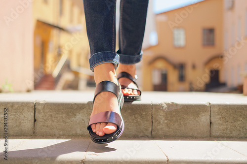 Female legs in sandals descending the stairs in the city