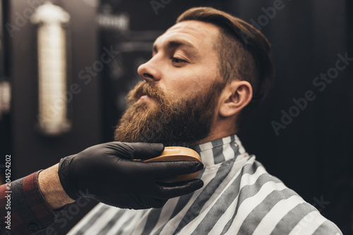 Modnisia młody przystojny mężczyzna odwiedza fryzjera męskiego sklep. Modna i stylowa broda oraz krój.