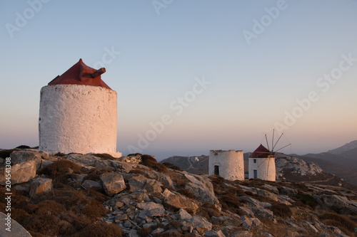 A series of deserted windmills at the top of Chora of Amorgos through a windmill wheel