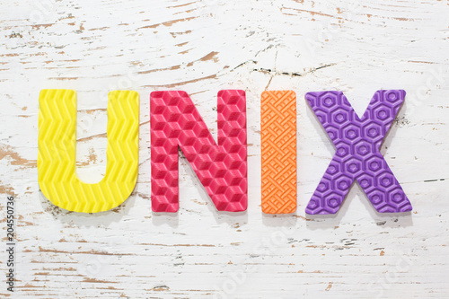 Word UNIX from colorful rubber alphabet letters on wooden board background.