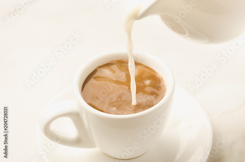 milk is added to coffee cup/milk is added to coffee cup on a white background. Selective focus