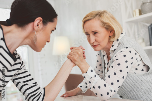 I will win. Serious concentrated woman looking at her daughter in law while holding her hand