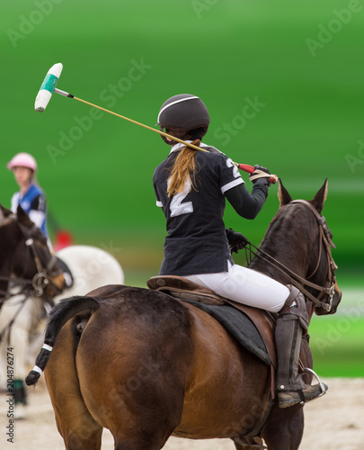 Polo woman player is riding on a horse.
