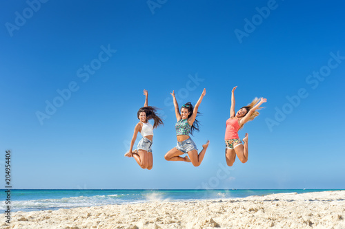 Happy young women jumping at the beach