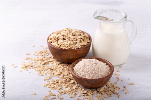 Vegan non dairy oat milk,flour and flakes on white wooden background. Healthy eating