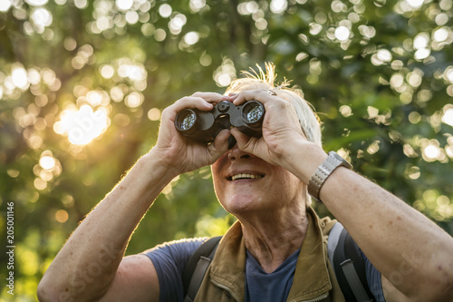 Elderly man watching birds with binoculars