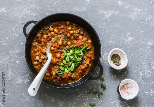 Vegetarian buffalo chickpea chili with mushrooms in a pan on a gray background, top view. Healthy vegetarian food concept