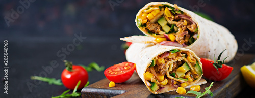 Burritos wraps with beef and vegetables on black background. Beef burrito, mexican food.