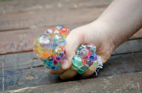 hand of kid squeezing stress relief grape balls, squeezing balls, mesh squishy balls hand wrist toy, isolated on wooden background