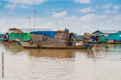 A sampan-like boat, including a small shelter with a curved roof made of wood and thatch that might be a permanent habitation, is anchored in Cambodia's floating village Chong Kneas on Tonle Sap Lake.