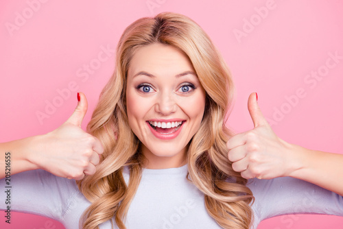 Close up portrait of pretty good girl with modern hairstyle gesturing two thumbs up like symbols looking at camera isolated on pink background. Advertisement concept