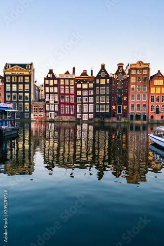 View of colorful facades of typical Amsterdam houses reflecting in the Amstel river canal in Amsterdam during sunset