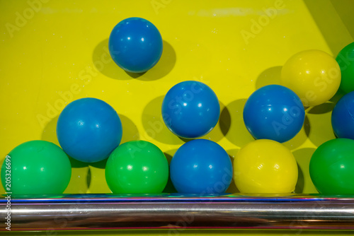 Plastic ball in various colors against yellow background