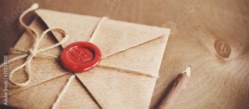 love letter in a craft envelope with a sealing wax seal in the form of a heart on a wooden background. Free space