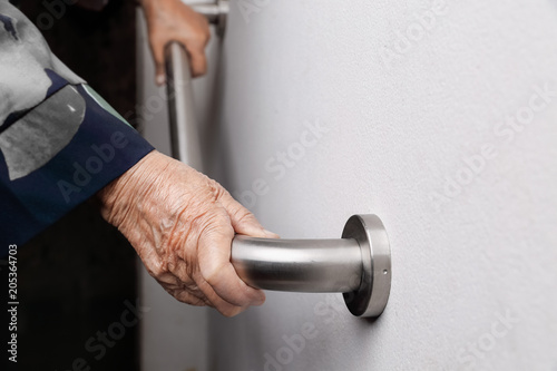 Elderly woman holding on handrail for safety walk steps