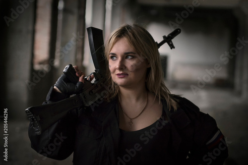 A girl with a machine gun looks with a stern gaze